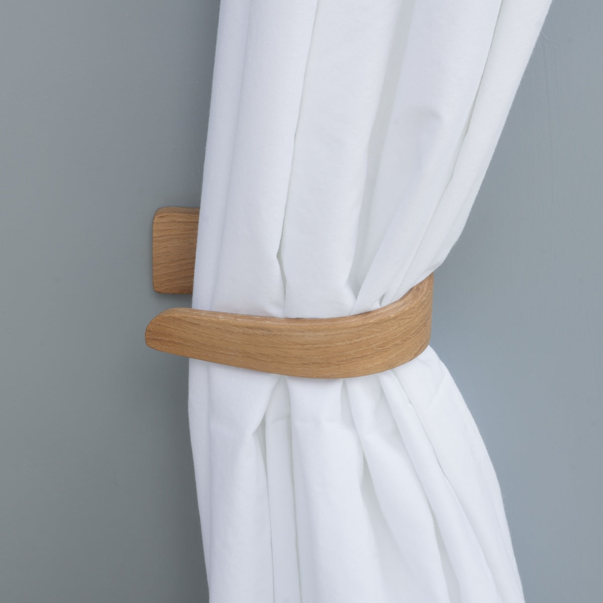Wooden curtain holder on a white curtain against a gray background